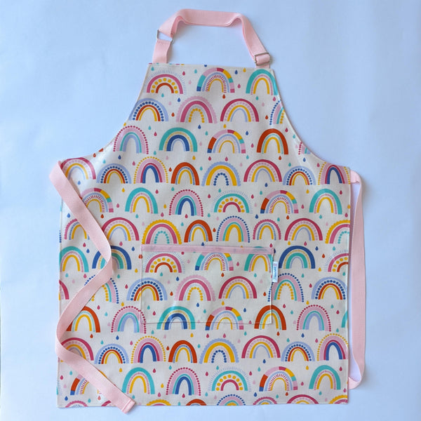 Medium, Lined, Wipeable, Kids Rainbow Oilcloth Apron with front pocket and baby pink adjustable neck band and waist ties and trim.